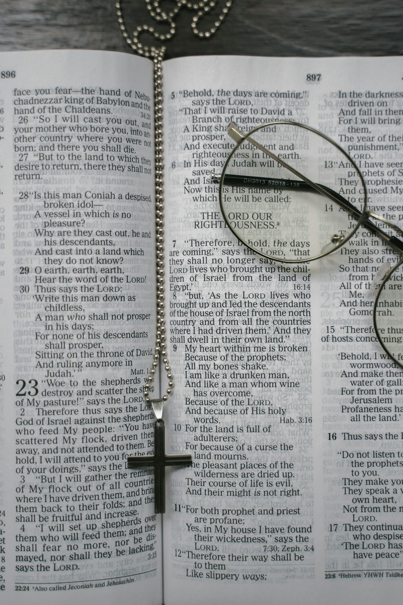 An open Bible with a cross necklace and glasses placed on the pages, symbolizing faith.